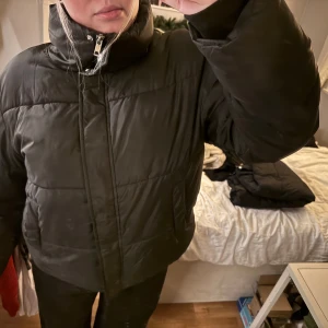 Svart pufferjacka med dragkedja - Säljer en svart pufferjacka med hög krage och dragkedja. Jackan är perfekt för kyliga dagar och har en bekväm passform.