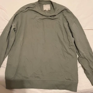 Grön tröja från 157 - Säljer en stilren grön tröja från 157 i storlek M. Tröjan har långa ärmar och ribbade muddar vid ärmslut och nederkant. Perfekt för en avslappnad look.super mysig 