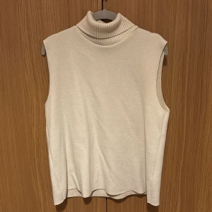 Beige ärmlös polotröja från Zara - Snygg beige ärmlös polotröja från Zara. Oanvänd i storlek L, så passar storlek L eller mindre storlek lite mer oversized. Säljs för 200kr men inkluderad frakt.