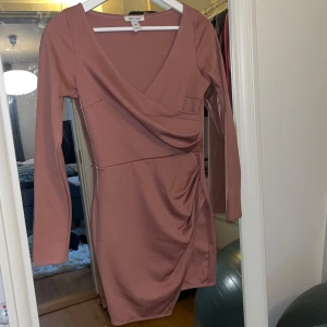 Rosa klänning från NLY One - Gammelrosa klänning från NLY One med omlott-design och v-ringning. Klänningen har långa ärmar och en smickrande drapering på sidan. Endast använd en gång så är i bra skick! Skulle säga det är en liten M, passar mellan S-M. Kom med prisförslag om du är intresserad🩷