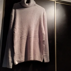 Ljusblå  stickad polotröja - Mysig ljusblå stickad polotröja med lång ärm och ribbad polokrage. Perfekt för kyliga dagar när du vill hålla dig varm och stilren. Den ser beige ut men den är ljusblå. Det står inte vilken storlek eller vilket märke det är men när det gäller storlek skulle den nog passa en M/L. 