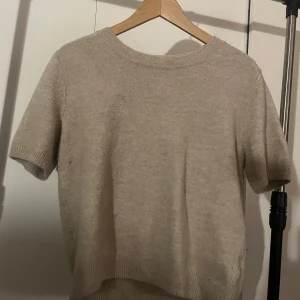 Beige kortärmad tröja från H&M - Säljer en stilren beige tröja från H&M. Den är kortärmad och har en rund halsringning med ribbade kanter. Perfekt för en avslappnad look. Storlek M men passar även mig som har XS.