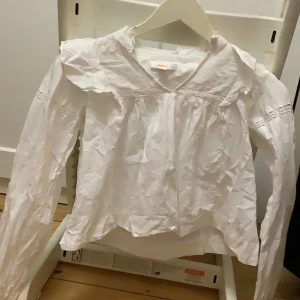 Vit blus  - V ringad Vit blus med volanger på axlarna och resor på slutet av armen från Gina Tricot perfekt till sommaren och till högtiderna  säljer pga storlek 