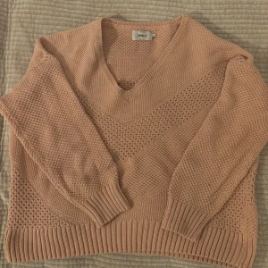 Rosa stickad tröja från ONLY - Mysig beige stickad tröja från ONLY med v-ringning och ribbade muddar. Perfekt för kyliga dagar. Storlek M, men lite oversized passform.