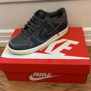 Nike Dunk Low ”halloween” - Snygga Nike Dunk Low sneakers i svart med gröna detaljer. Skorna har en klassisk design med snörning och en bekväm passform. Perfekta för en stilren look. De är helt oanvända och jätte fräscha