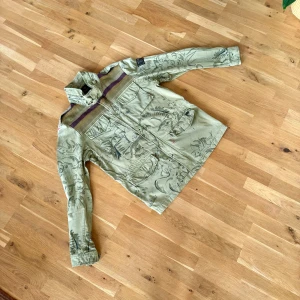 Unik jacka från Scotch & Soda - Säljer en grön jacka från Scotch & Soda med unikt mönster och detaljer. Jackan har långa ärmar och flera fickor framtill. Kan skicka mer bilder ifall det behövs. 