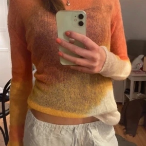 Flerfärgad stickad tröja - Super fin!! Använd endast en gång!Säljer en flerfärgad stickad tröja i orange, gul och vit. Tröjan har en tight passform och långa ärmar, perfekt för höst och vår. Den är mjuk och bekväm, idealisk för en avslappnad stil.