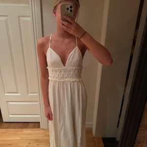 Vit långklänning med spetsdetaljer - Vit långklänning med smala axelband och v-ringad design. Fint skick använd en gång ❤️