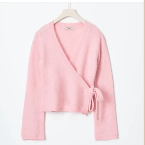 Rosa omlottkofta från Gina Tricot - Säljer en söt rosa omlottkofta från Gina tricot Den har långa ärmar och ett knytband i sidan för en justerbar passform. Perfekt för en mysig och stilren stil. Tröjan är i mycket bra skick, använd Max 5 gånger, säljer på grund av att jag inte tycker att den passar mig i smak
