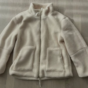 En jättefin vit Teddy jacka 🤍 - En fin krämvit Teddy jacka som är helt ny fast var tyvärr för liten för mig och måste sälja. NYPRIS : 799kr. Storlek S men passar XS och XXS också. Skriv om du vill ha fler bilder och om du är intresserad att köpa den! Pris kan diskuteras.