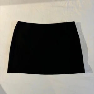 Minikjol - Svart minikjol med liten slit på sidan. Lågmidjad. Knappt använd. 