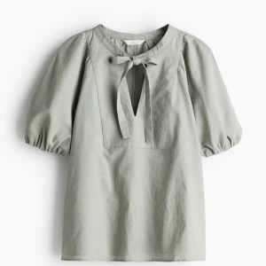 Grön blus med knytband - Säljer en superfin grön blus med puffiga kortärmar och ett sött knytband vid halsen. Perfekt för både vardag och lite finare tillfällen. Materialet känns lätt och luftigt, vilket gör den idealisk för vår och sommar. 🩷 Nyköpt med prislappen på