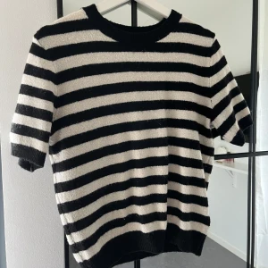 Randig stickad tröja - Säljer en superfin randig tröja i svart och vit. Den är stickad och har korta ärmar. Tröjan är i bra skick och passar till många olika outfits. Perfekt för en avslappnad men stilren look!
