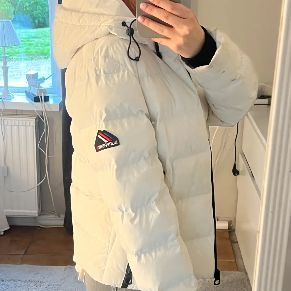 Vit dunjacka från superdry, den är använd fåtal gånger. Superfint skick (lite skitig men det är fläckar som förmodligen går bort i tvätten). Det står ingen storlek i men jag är vanligtvis en xs så skulle säga att den passar xxs-s.  Nypris 1199kr.. Jackor.