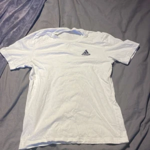 Vit t-shirt från Adidas - Säljer en klassisk vit t-shirt från Adidas med korta ärmar och logga på bröstet. Perfekt för träning eller vardagsbruk.