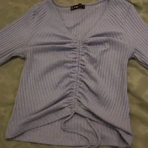 Ljusblå ribbad topp  - Säljer en ljusblå ribbad topp från FB Sister med v-ringning och långa ärmar.