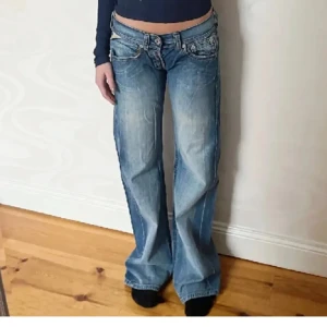 Blå lågmidjade bootcut/ baggy replay jeans - Midjemåttet är 36 cm tvärs över och innnerbensländen är 80 cm. Har använt dessa en del så de har slitningar längst ner och på bakdelen, men det kan man sy ihop! De är ifrån replay.
