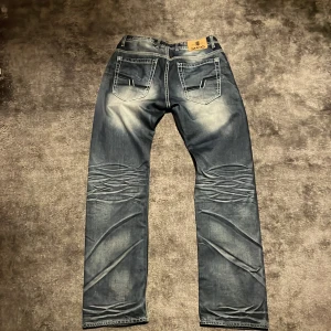 Blå jeans från Smog - Säljer ett par snygga blå jeans från Smog med en cool tvättad look. De har klassisk femficksdesign och en bekväm passform. Perfekta för en avslappnad stil.