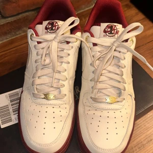 Nike Air Force i vitt och rött - Snygga Nike Air Force sneakers i vitt med röda detaljer. Skorna har klassisk snörning och en bekväm passform. Perfekta för en stilren look. Knappt haft de på mig✨