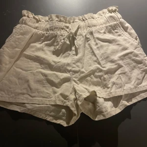 Beige shorts med resårmidja - Snygga beige shorts med resårmidja och knytband. Perfekta för en avslappnad stil. De har en lös passform och är tillverkade i ett lätt material.