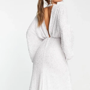 Balklänning  - Elegant vit klänning täckt av glittrande paljetter. Den har en djup v-ringning och är ärmlös, vilket ger en sofistikerad look. Perfekt för festliga tillfällen. Nertill har paljetter lossnat samt en av spännena och ena är halvt lossad. Annars fint skick. Köpt för 3000kr säljer för 1900. Skriv för fler bilder samt diskutera. OBS klänningens trådar och paljetter lossnar välidigt lött så var uppmärksamm om det när de kmr till skicket 