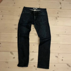 Jay jeans från J Lindeberg  - Snygga mörkblå jeans från J.Lindeberg med klassisk femficksdesign och knappgylf. Perfekta för en stilren look. Skulle säga att storleken motsvarar W32/L32. 