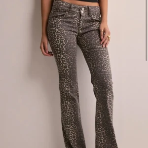 Leopardmönstrade bootcut jeans - Snygga leopardmönstrade bootcut jeans med låg midja. Perfekta för att ge din outfit en trendig touch. De har en klassisk femficksdesign och stängs med knapp och dragkedja framtill. Använda 2ggr, nypris 700kr, storlek 38