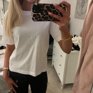 Vit t-shirt - Säljer en klassisk vit t-shirt med normal passform. T-shirten har korta ärmar och är perfekt för en enkel och stilren look. Passar till det mesta och är ett måste i garderoben. Endast använd 1 tillfälle.