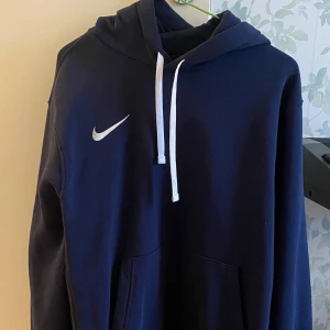 Mörkblå hoodie från Nike - Säljer en mörkblå hoodie från Nike i storlek M. Endast använd ett fåtal gånger. Fraktas spårbar med postnord eller hämtas i Stockholm. 
