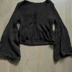 Brun stickad kofta med utsvängda ärmar - Säljer en brun stickad kofta med tre knappar framtill. Koftan har en ribbad överdel och vida ärmar. Perfekt för en mysig höstlook.❤️🍁