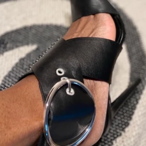 Svarta klackskor med spänne från Zara - Snygga svarta klackskor från Zara med ett stort dekorativt spänne. Skorna har en elegant design med spetsig tå och hög klack, perfekta för att lyfta din outfit.