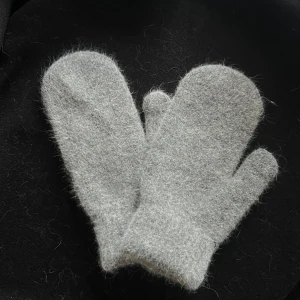 Grå ullvantar - Mysiga grå ullvantar i tumdesign, perfekta för kalla dagar. De är fluffiga och håller händerna varma under vintern. Enkla att matcha med olika vinterkläder.