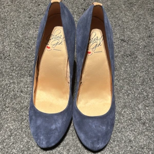 Blå mocka pumps från Chang Girl - Eleganta blå pumps i mocka från Chang Girl. Skorna har en spetsig tå och hög klack, vilket ger en stilren och sofistikerad look. Perfekta för att lyfta din outfit till nästa nivå.