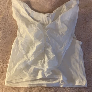 Vit blus från Zara - Säljer en stilren vit blus från Zara med volangdetaljer vid axlarna. Perfekt för en chic och elegant look. Blusen är ärmlös och har en luftig passform. Storlek 164💘🥰