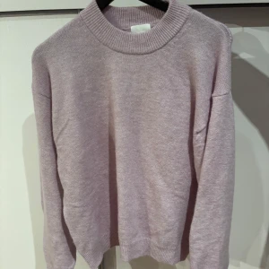 Ljuslila stickad tröja - Mysig ljuslila stickad tröja med ribbad krage och långa ärmar. Perfekt för kyliga dagar och ger en stilren look. Passar bra till både jeans och kjol.