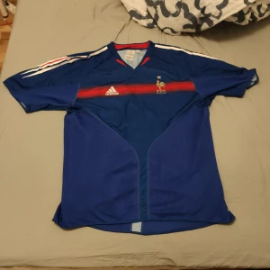 Frankrike EM 2004 Zidane #10 - Äkta! Frankrikes hemmatröja från EM 2004 med Zidane #10 på ryggen. Fransmännen slogs ut av grekerna, i kvarten som skrällde och vann hela turneringen.  Storlek: XL.  Skick: 9/10. 