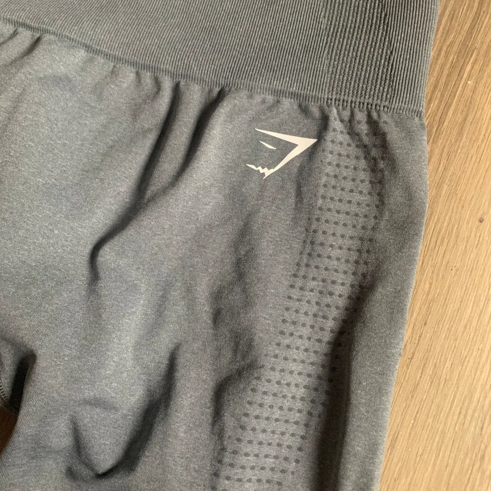 Säljer ett par grå leggings från Gymshark i storlek M. De är perfekta för träning med sin stretchiga och bekväma passform. Materialet är syntetiskt och har ett diskret prickigt mönster. Midjan är hög och ger bra stöd under träningen.. Sportswear.