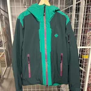 Skidjacka - Grön skidjacka från J.Lindeberg som är använd 1 timma totalt så den är i nyskick! Köptes för ungefär 4000:- men säljer den nu för 1000:-. Halvfodrad med bra fickor och vattenavisande tyg.