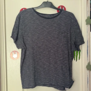 Vitrandig T-shirt  - Marinblå T-shirt med tunna vita ränder på! Köpt på myrorna för ett år sen.  Bra skick, säljer då den aldrig kommer till användning! Skriv om det är nått, pris går alltid att diskutera! 