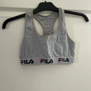 Grå sporttopp från Fila - Säljer en grå topp från Fila. . Perfekt för träning eller en avslappnad dag.