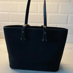 Handväska  - En jättefin svart handväska. Den ser precis ut som ny då den endast är anvämd några få gånger på universitetet. En rymlig väsks där bland annat dator får plats. 