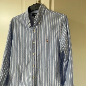 Polo Ralph lauren skjorta  - Säljer en snygg polo Ralph lauren skjorta. Vit/blå färg. Storlek S och modell slim fit. Inga defekter och i bra skick. Hör gärna av er kring frågor🤩