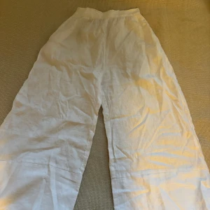 Vita linnebyxor från Posse - Säljer ett par vita linnebyxor från Posse. De är högmidjade med en dragkedja i sidan för enkel på- och avtagning. Perfekta för sommaren med sin luftiga och bekväma passform. Byxorna har en loose stil som ger en avslappnad look. Perfekta för både strandhäng och sommarfester!