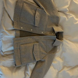 Grå jacka från Zara - Säljer en snygg grå jacka från Zara i mycket bra skick. Den har en stilren design med knappar framtill och stora fickor. Perfekt för höst och vår!