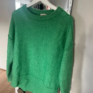 Malene Birger, Grön stickad tröja - Säljer en supermysig grön stickad tröja i mycket bra skick. Perfekt för kyliga höst- och vinterdagar. Tröjan har långa ärmar och en bekväm passform med ribbade muddar vid ärmslut och nederkant. Ett måste i garderoben för alla som älskar att hålla sig varm och stilren! 🍃