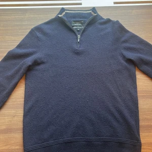 Cashmere Zip - En halfzip ifrån Savile Row Company London. Merino ull/Cashmire. Rätt bra skick förutom hål vid vänster arm, se sista bilden. Nypris runt 1500kr. Färg är beige i kragen och mörkblå. Mörkbruna patches  på armbågarna. Storlek M passar S, Runt 177 cm. 