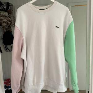 Säljer en snygg vit sweatshirt från Lacoste med pastellfärgade ärmar i rosa och grönt. Tröjan har en klassisk passform😁🌸skulle uppskatta den till 4-5xl