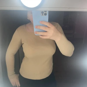 Beige ribbad tröja - Säljer en snygg beige ribbad tröja med lång ärm. Perfekt för höst och vår, den är både stilren och bekväm. Passar bra till både jeans och kjol. Perfekt för en casual look eller att klä upp med accessoarer. (Är blek sitter finare när man är mer tan) köpt gammal från zara knappt använd