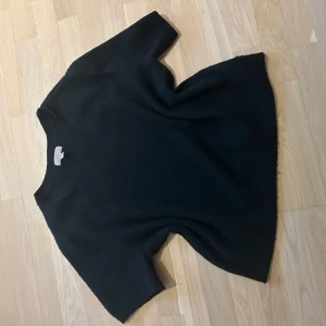 Svart kortärmad stickadtröja  - Säljer en svart stickadtshirt! Den är lite nopprig, men annars fint skick! Strlk L men sitter som en M