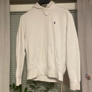 Vit hoodie från Ralph Lauren - Säljer en stilren vit hoodie från Ralph Lauren i mycket bra skick med nypris 1800. Den har en klassisk passform med långa ärmar och en praktisk magficka. Perfekt för både vardag och avslappnade tillfällen. Den ikoniska loggan är broderad på bröstet. Passar perfekt till höst och vår!